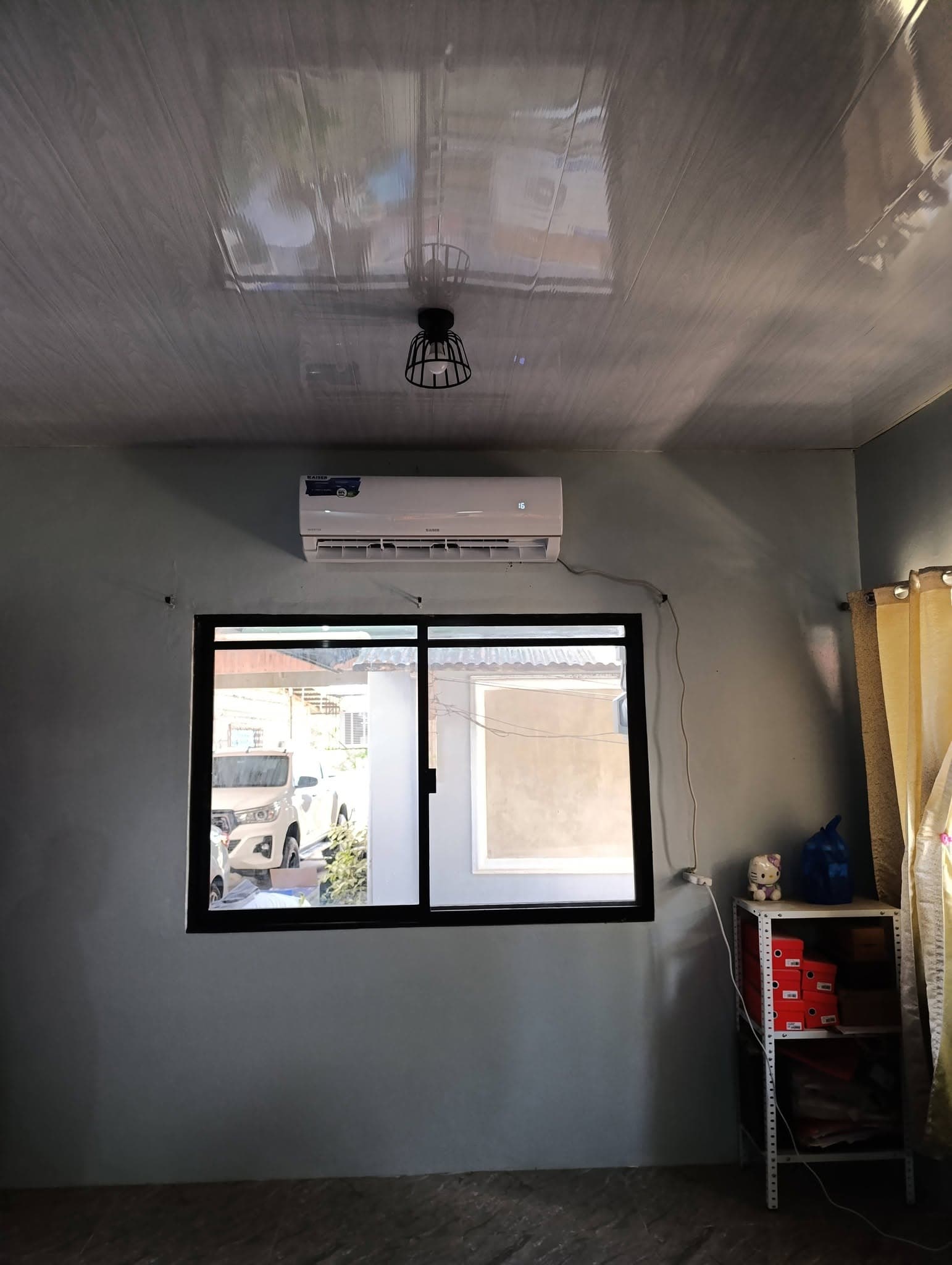Finished Kaiser inverter indoor air-conditioning unit operating above a black-framed window.