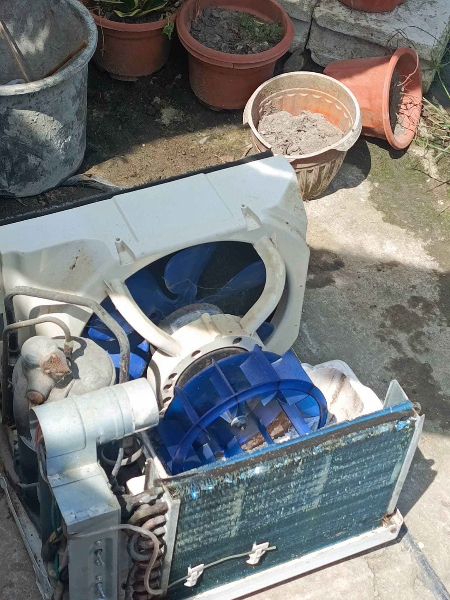 Window air conditioner opened for blower, fan, and coil cleaning outdoors.
