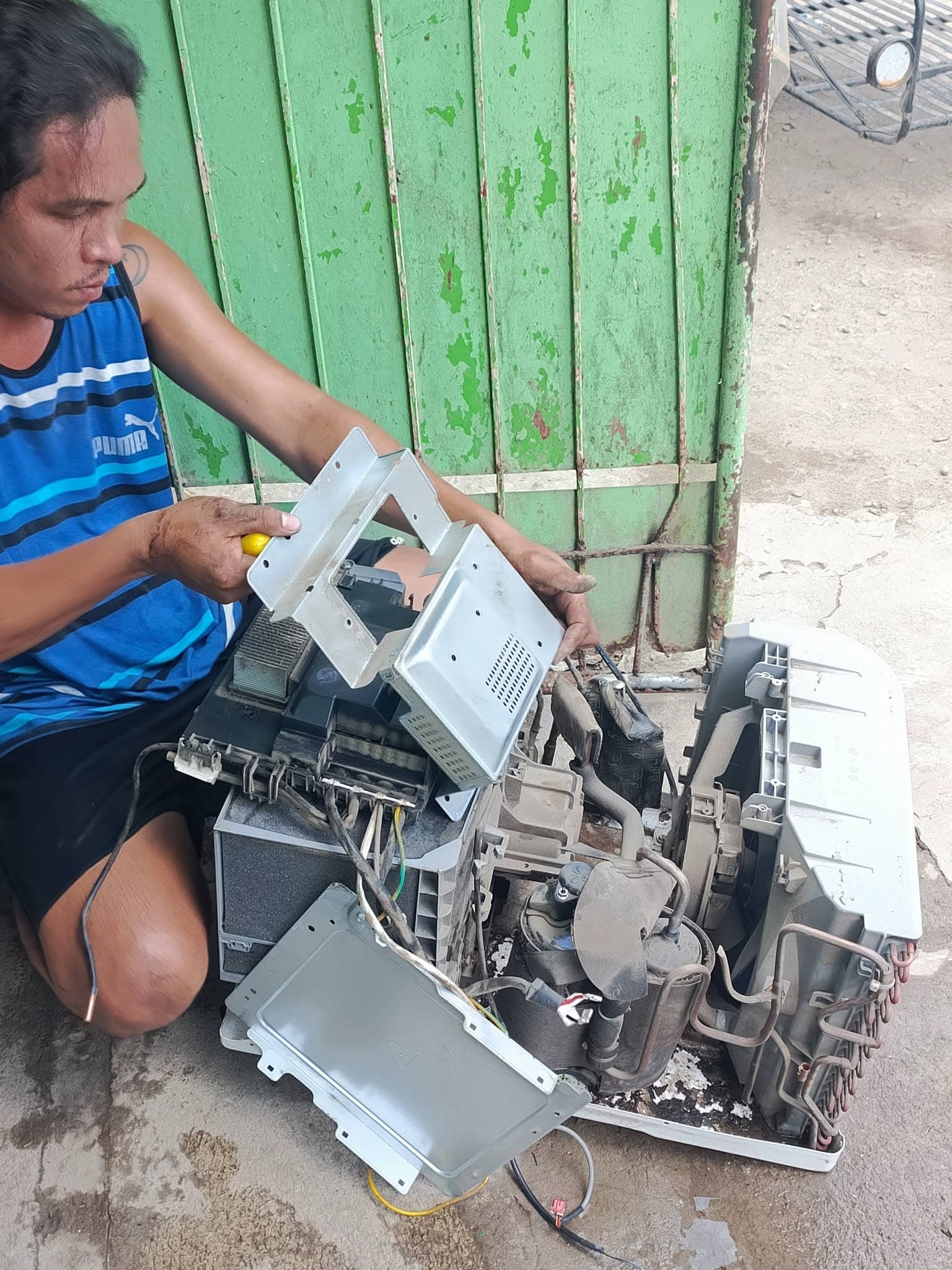 Technician removing electrical covers during a complete window AC teardown.
