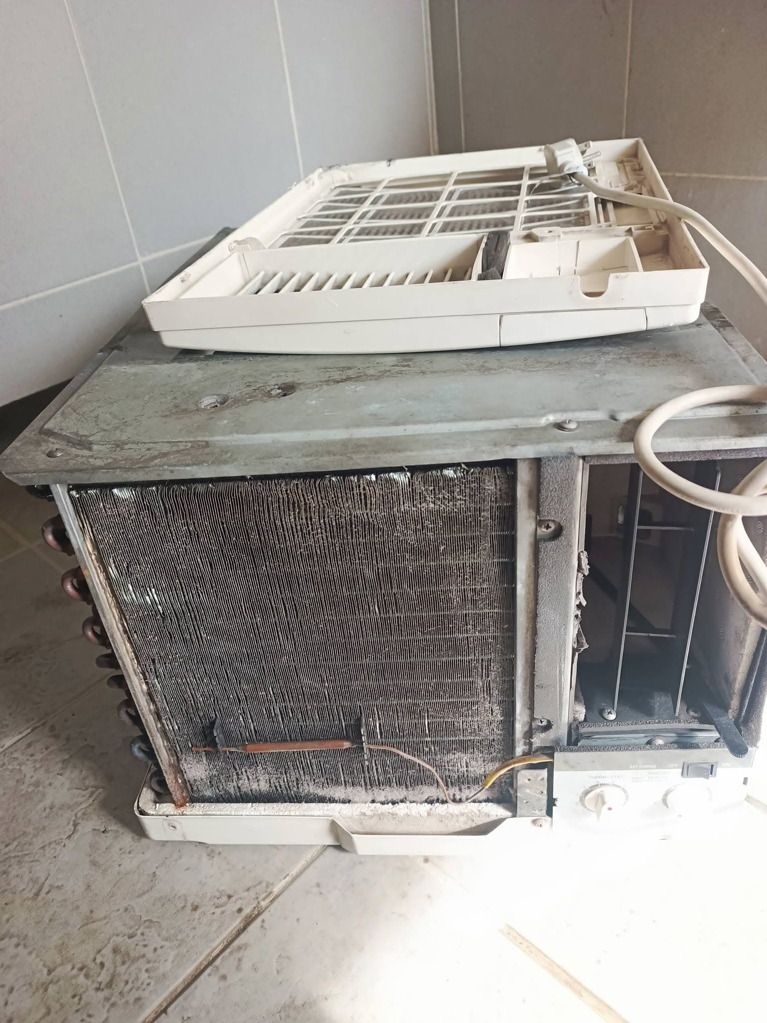 Window-type air conditioner with a heavily soiled evaporator coil before cleaning.
