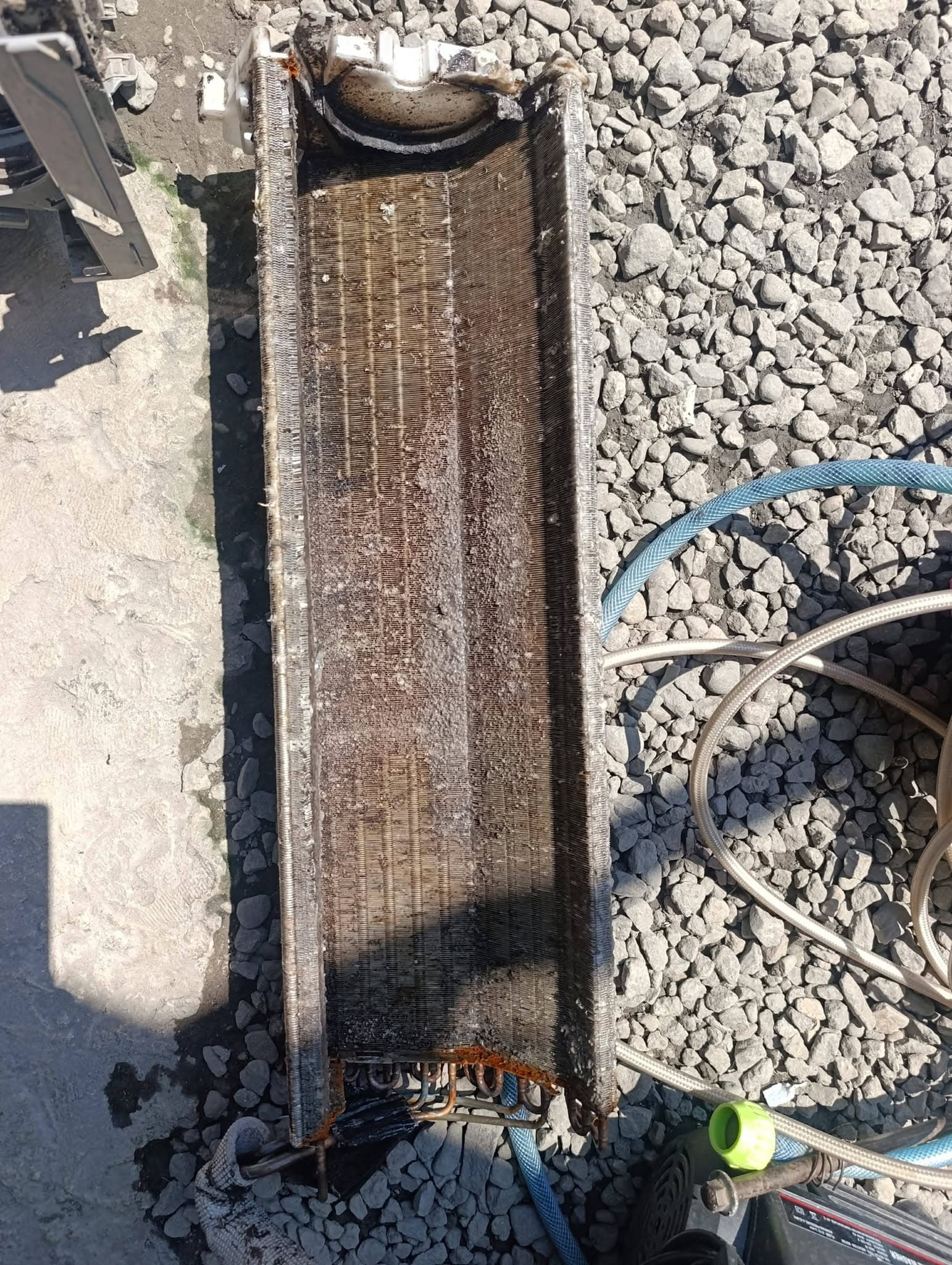 Removed split-type evaporator coil covered in compacted dirt before washing.