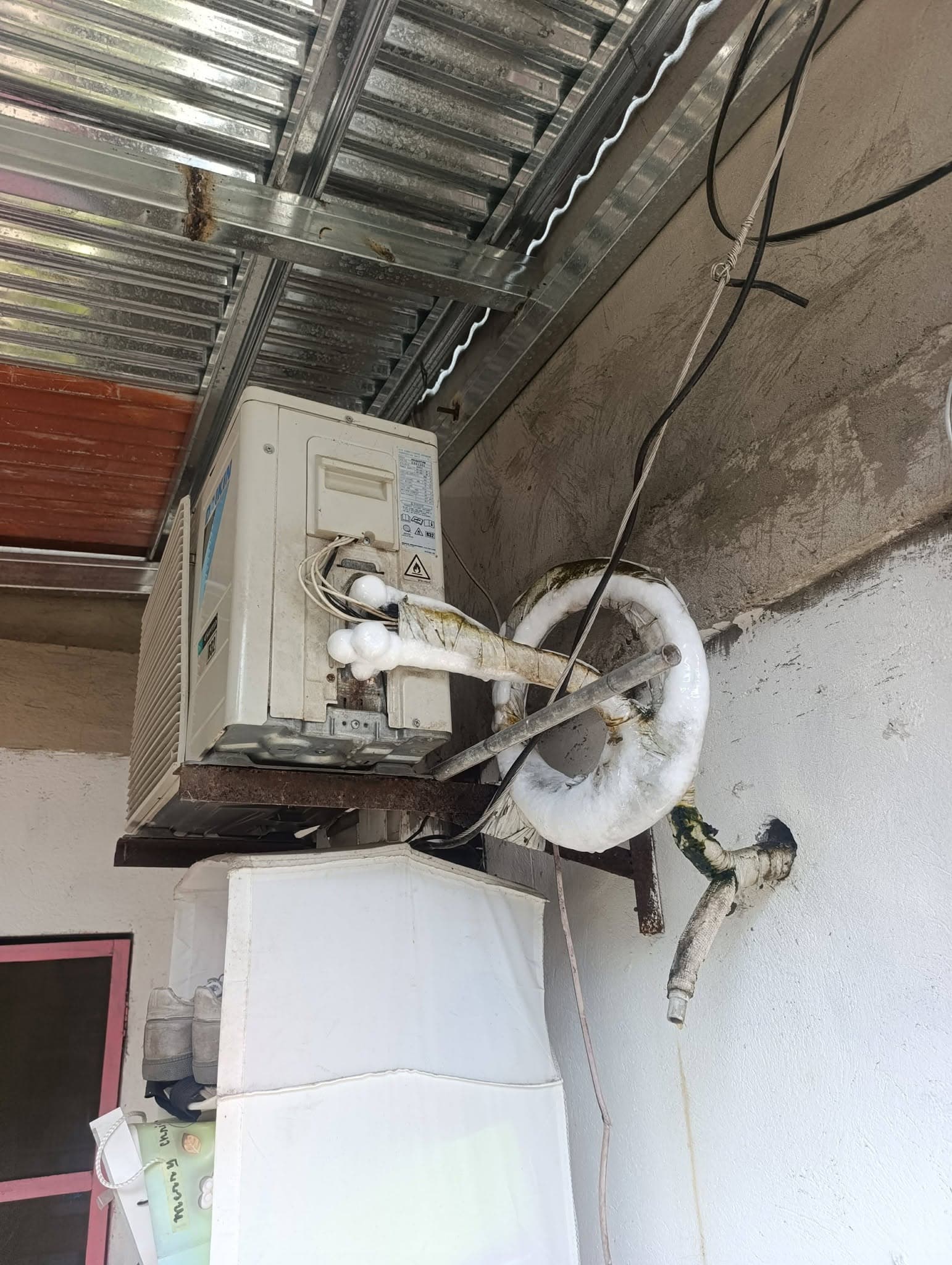 Split-type outdoor condenser with iced refrigerant lines before servicing.