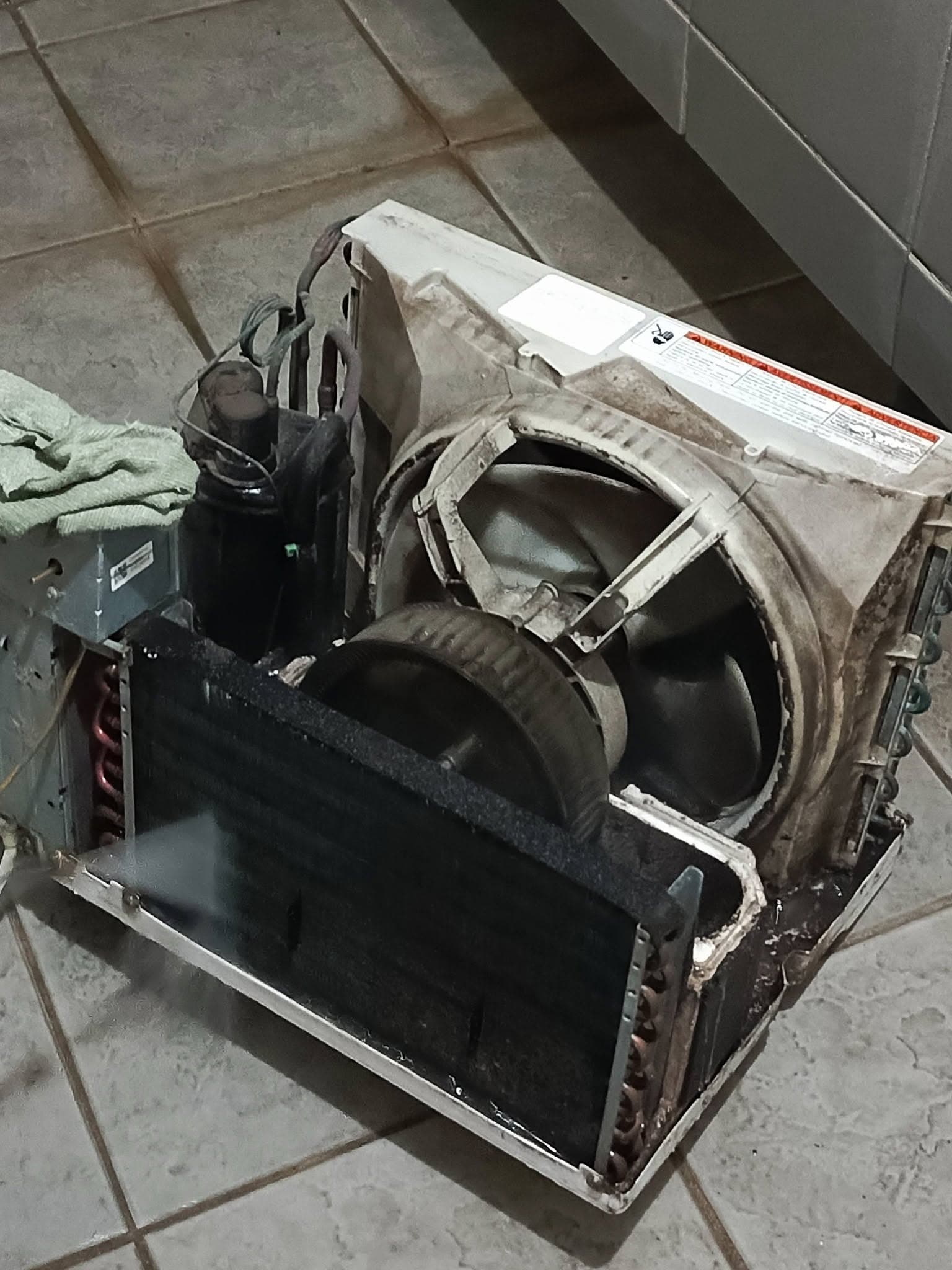 Opened window air conditioner showing accumulated dirt around the blower and coil.