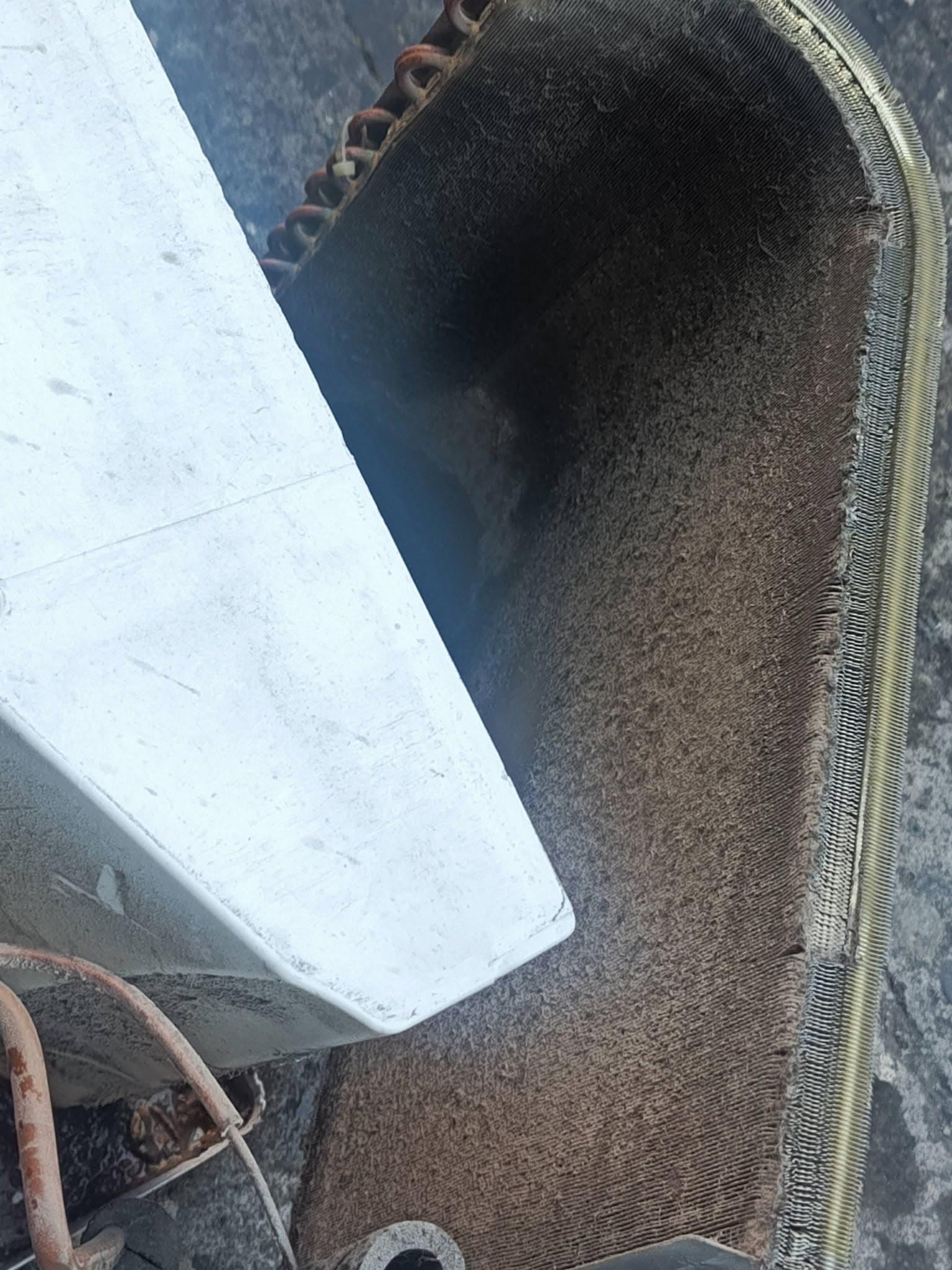 Close view of thick dust blocking airflow through the window air conditioner coil.